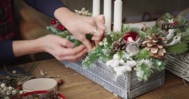 Dişi çiçekçi güzel bir Noel sepeti hazırlıyor.