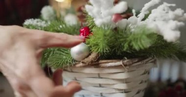 Çiçekçi kırmızı böğürtlenli, köknar dallı ve kozalaklı Noel sepeti yapar.