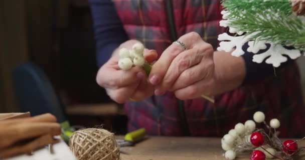 Bloemist maakt een decoratie voor de kerst van rode bessen en twijgen — Stockvideo