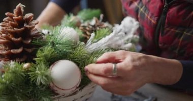 Çiçekçi kırmızı böğürtlenli, köknar dallı ve kozalaklı Noel sepeti yapar.