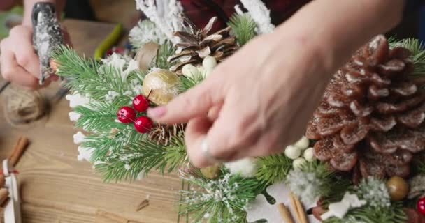Флорист делает Рождественскую корзину с красными ягодами, еловыми ветвями и хвойными конусами — стоковое видео