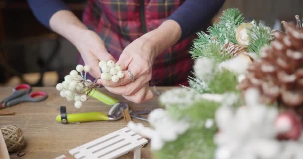 Bloemist maakt een decoratie voor de kerst van rode bessen en twijgen — Stockvideo