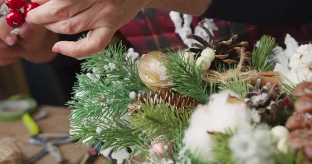 Floristería hace cesta de Navidad con bayas rojas, ramas de abeto y conos de coníferas — Vídeos de Stock