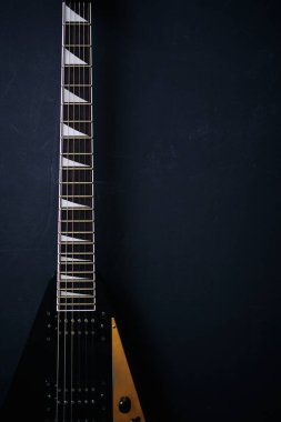 Koyu grunge arka planında siyah V biçimli elektro gitar.