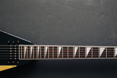 Koyu grunge arka planında siyah V biçimli elektro gitar.