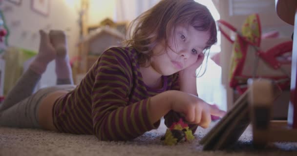 Ragazza è sdraiata sul pavimento nella sua stanza e cercando qualcosa su tablet — Video Stock