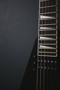 Koyu grunge arka planında siyah V biçimli elektro gitar.