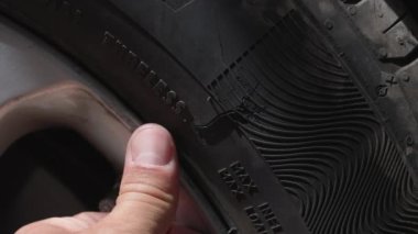 Hasarlı patlak araba lastiğini erkek denetliyor.. 