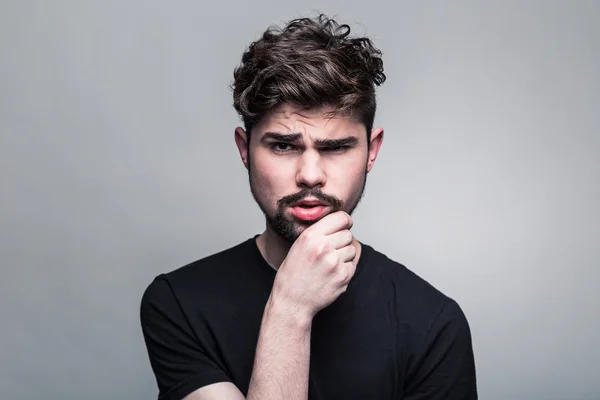 Young man in  black T-shirt doubting — Stock Photo, Image
