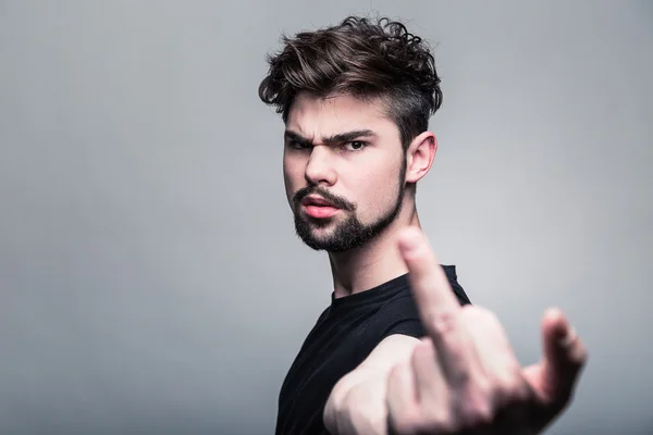 Young man in  black T-shirt showing middle finger — Stock Photo, Image