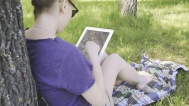 Kadın gözlük parkta tablet PC'yi kullanma.