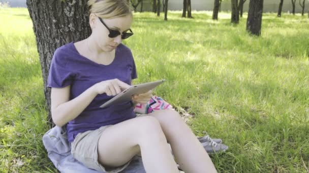Kvinna i glas med hjälp av TabletPC i parken. — Stockvideo