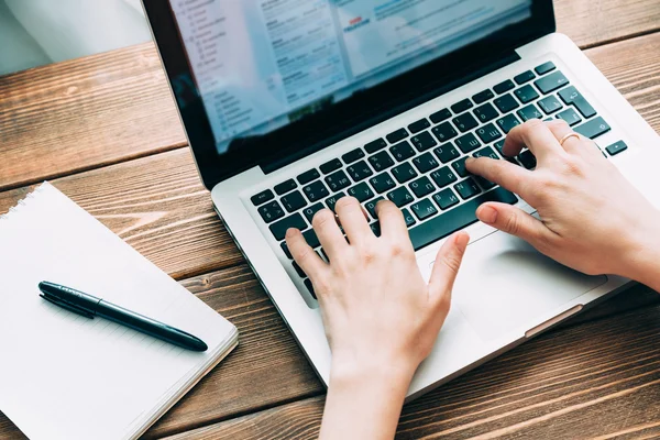 Woman working with laptop placed on wooden desk — Stock Photo, Image