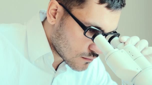 Joven médico masculino viendo a través del microscopio — Vídeos de Stock