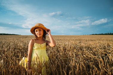 Little girl in hat on wheat field 