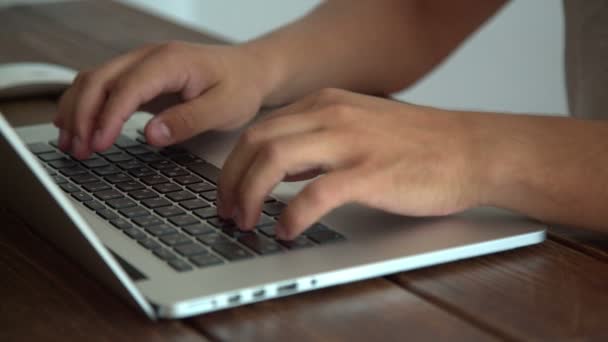 Hombre trabajando con el ordenador portátil colocado en el escritorio de madera — Vídeos de Stock