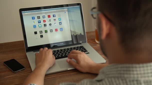 Mann arbeitet mit Laptop auf Holzschreibtisch. Saint petersburg, russland - august 29, 2015 — Stockvideo