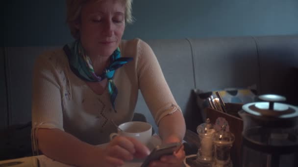 RUSIA, SAN PETERSBURG - 31 de agosto de 2015: Mujer adulta usando smartphone en la cafetería — Vídeos de Stock