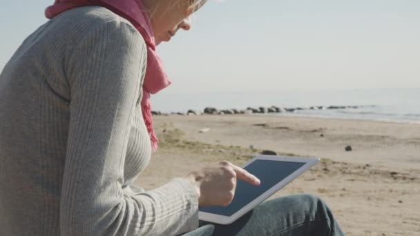 Kobieta przy użyciu komputera typu tablet na plaży — Wideo stockowe