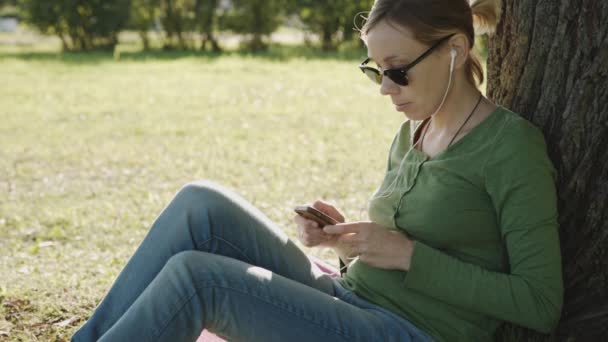 Dziewczyna w parku wykorzystania telefonów komórkowych — Wideo stockowe
