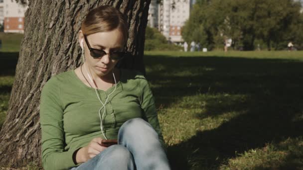 Flickan i parken använda mobilen — Stockvideo