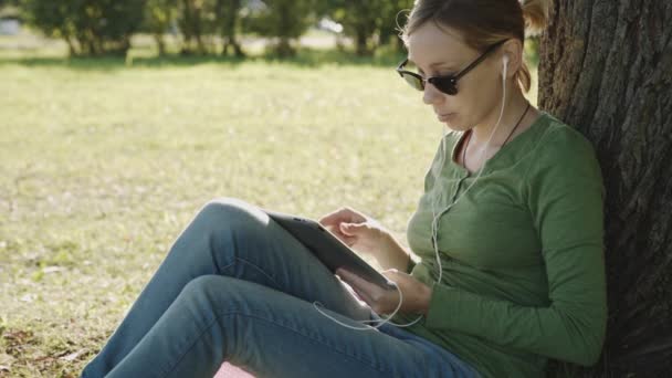 Chica en el parque y el uso de la tableta PC — Vídeos de Stock