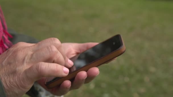 Ενήλικη γυναίκα χρησιμοποιώντας smartphone στο πάρκο — Αρχείο Βίντεο
