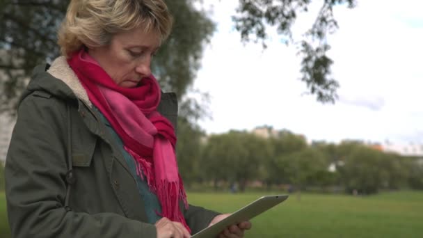 Erwachsene Frau benutzt Tablet-PC im Park — Stockvideo