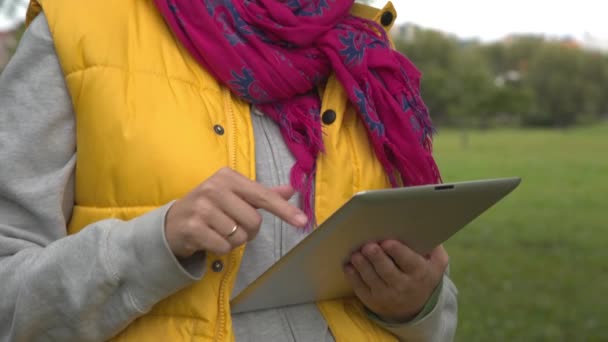 Mulher em colete amarelo usando tablet pc no parque — Vídeo de Stock