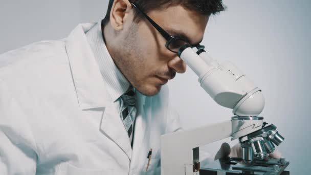 Médico joven mirando a través del microscopio — Vídeo de stock