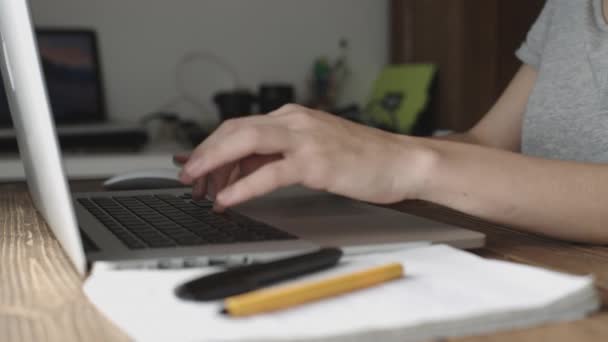 Mujer trabajando con portátil colocado en escritorio de madera — Vídeos de Stock