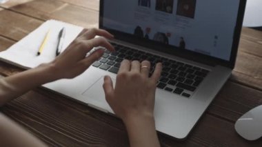 Ahşap masanın üstüne yerleştirilen dizüstü bilgisayar ile çalışan kadın