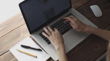 Ahşap masanın üstüne yerleştirilen dizüstü bilgisayar ile çalışan kadın