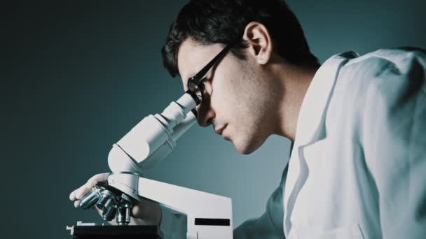 Νέος γιατρός, κοιτάζοντας μέσα από το μικροσκόπιο — Αρχείο Βίντεο