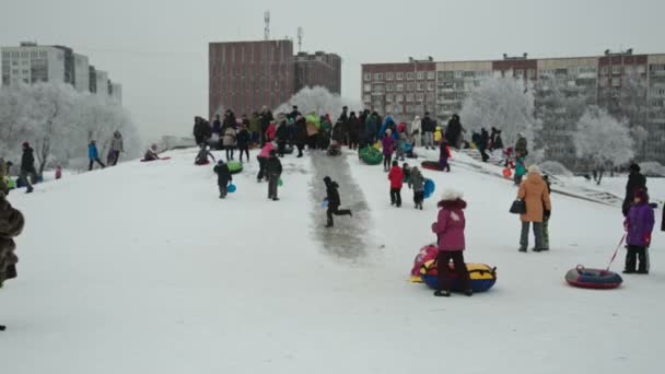 Děti sjíždět kopce sněhu v parku na víkend — Stock video
