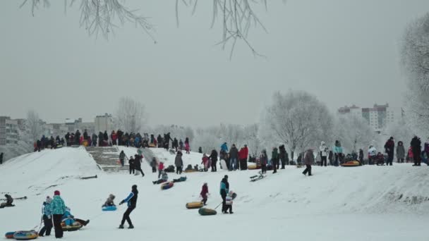 Crianças deslizar para baixo uma colina de neve no parque no fim de semana — Vídeo de Stock