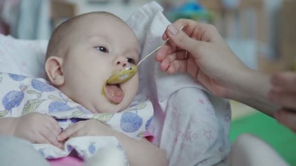 Mother feeding baby food to baby — Stockvideo