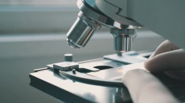 Bilim adamı laboratuvarda mikroskop kullanıyor.