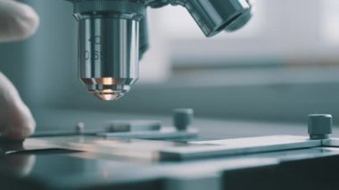 Bilim adamı laboratuvarda mikroskop kullanıyor.