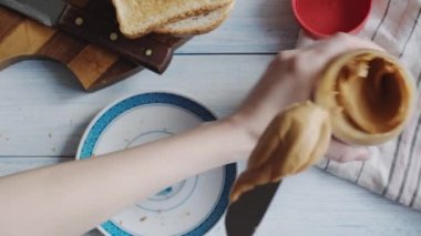 Kadın bir fıstık ezmesi sandviç yapar