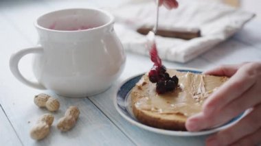 Kadın fıstık ezmesi ve reçel ile sandviç yapar