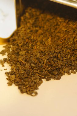 Arka planda yeşil çay. Kurutulmuş yeşil çay yaprakları. Sıcak bir içecek hazırlıyorum. Yakınlaştırılmış görüntüde birkaç porsiyon çay. Metal bir teneke içinde çay.