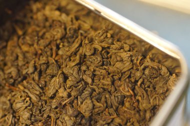 Kurutulmuş yeşil çay yaprakları. Sıcak bir içecek hazırlıyorum. Yakınlaştırılmış görüntüde birkaç porsiyon çay. Metal bir teneke içinde çay.