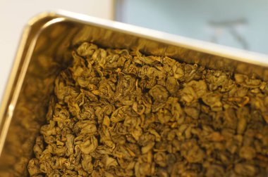 Kurutulmuş yeşil çay yaprakları. Sıcak bir içecek hazırlıyorum. Yakınlaştırılmış görüntüde birkaç porsiyon çay. Metal bir teneke içinde çay.