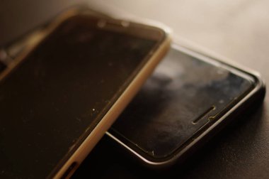 İki büyük siyah cep telefonu kullanılmış. Kullanım belirtileriyle korunan bir ekran filmi. Yıkım ve yıpranma ekranda. Telefonların servise ihtiyacı var. Koruyucu filmli eski gsm telefonları.