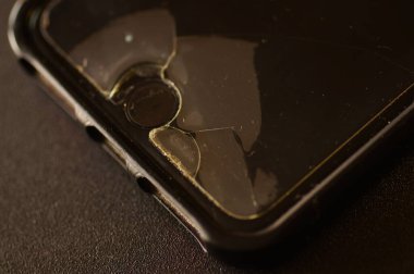 Cep telefonu - koruyucu camlı ekran. Koruyucu filme yakın çekim. Hasar belirtileri olan cam. Telefon koruması yenilenmeyi ya da onarılmayı gerektirir. Kullanılmış, hasarlı telefon ve koruyucu film..