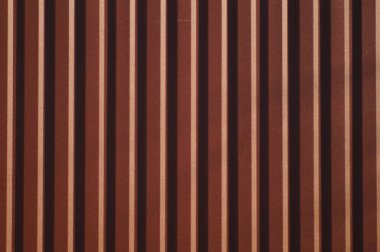 Simetrik kahverengi düz çizgileri olan bir arka plan. Trapezoidal metal levha duvarı. Kabartmalı desenli metal levha tasarımı. Oluklu metal levhada basit dekoratif şablon.