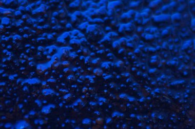 Soyut mavi gizemli arka plan. Koyu ışıkta pürüzlü bir doku. Yağlı, yağlı kabarcıklar ve kabarcıklarla dolu. Yansıyan mavi ışıkla birlikte koyu ve düz olmayan bir arka plan. Jestsel dokuya sahip 3d illüstrasyon.