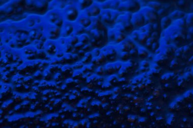 Soyut mavi gizemli arka plan. Koyu ışıkta pürüzlü bir doku. Yağlı, yağlı kabarcıklar ve kabarcıklarla dolu. Yansıyan mavi ışıkla birlikte koyu ve düz olmayan bir arka plan. Jestsel dokuya sahip 3d illüstrasyon.