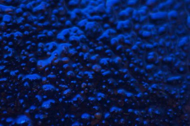 Soyut mavi gizemli arka plan. Koyu ışıkta pürüzlü bir doku. Yağlı, yağlı kabarcıklar ve kabarcıklarla dolu. Yansıyan mavi ışıkla birlikte koyu ve düz olmayan bir arka plan. Jestsel dokuya sahip 3d illüstrasyon.